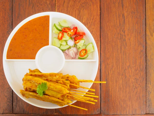 Свинина на гриле Satay с арахисовым соусом и уксусом на деревянном столе — стоковое фото