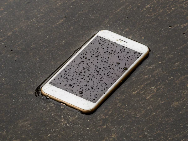 Wet smart phone dropped on flooding floor — Stock Photo, Image