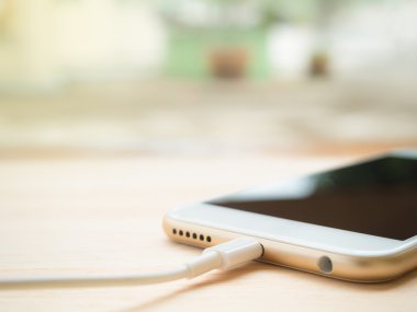 Ahşap masa üstünde batarya şarj Smartphone