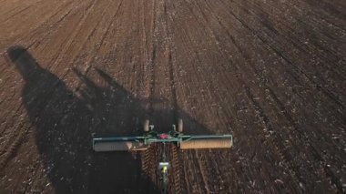 Günbatımında tarım alanında çalışan modern traktör. Hava aracı görüntüsü