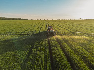 Sürdürülebilir tarım. Traktör ve sprey kullanan bir çiftçinin hava görüntüsü..