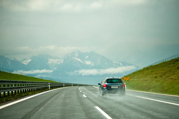 Coche en la autopista sobre un fondo de montañas . — Foto de Stock