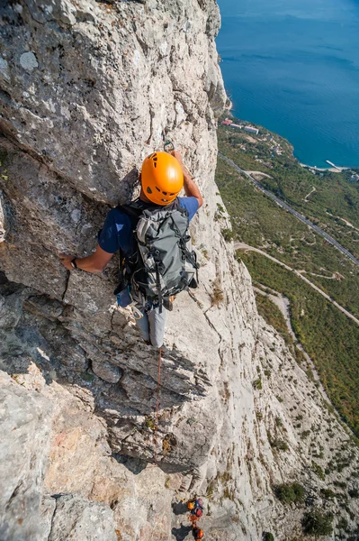 Der Kletterer erklimmt den Felsen gegen das Meer — Stockfoto