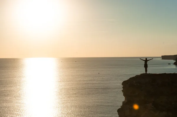 Девушка на скале над морем на закате . — стоковое фото