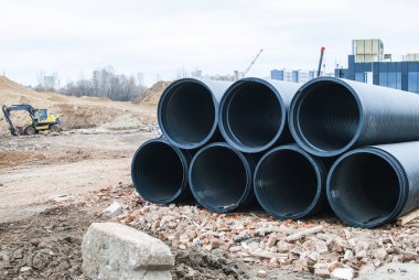 Siyah plastik borular yerdeki inşaat sahasında, kazıcıdan çok uzakta değil.