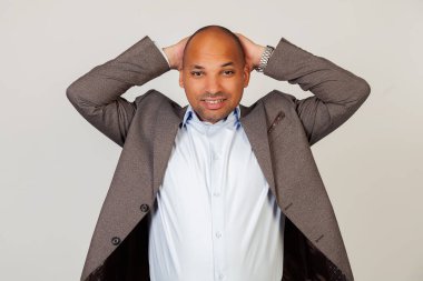 Kafasında el ele tutuşan kameraya bakan üzgün bir Afro-Amerikan iş adamının portresi. Gri bir arka planda duruyor