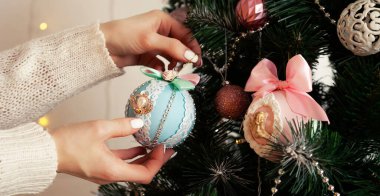Dişi ellerin yakın çekimi topu ağaca asar. Noel süsü, ağaçta asılı oyuncaklar, Noel ağacı topu. Yeni yıl ve Noel tatili konsepti