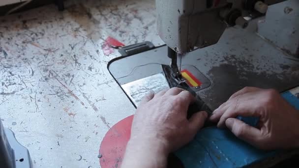 Close-up da mão de um mestre de um homem de desejos, um curtidor costura couro natural em uma máquina de costura em uma oficina para fazer produtos artesanais. Fazendo artigos de couro feitos à mão. — Vídeo de Stock