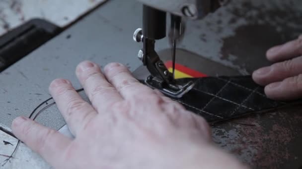 De mensenhanden van een kleermaker naaien een product van natuurlijk leer op een naaimachine. Handgemaakte lederen productie. Handgemaakte naaiatelier — Stockvideo