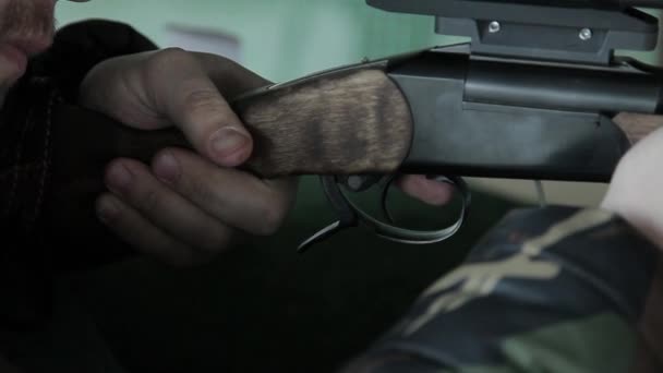 Seorang pemburu penembak laki-laki membidik dan menarik pelatuk pistol karabin membuat tembakan dari senjata api. Latihan menembak dalam jarak tembak di meshes. Pria itu menembak target.. — Stok Video