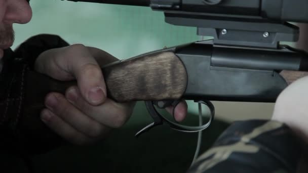 Un cacciatore di sparatutto prende la mira e preme il grilletto di una pistola di carabina facendo un colpo da un'arma da fuoco. Allenamento di tiro nel poligono di tiro sulle maglie. L'uomo spara al bersaglio.. — Video Stock