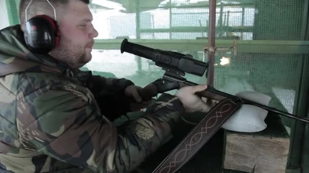 Um caçador de atiradores do sexo masculino insere um cartucho em um rifle uma carabina tem como objetivo se preparar para um tiro de uma arma de fogo. Treino de tiro no campo de tiro nas malhas. Homem de camuflagem — Vídeo de Stock