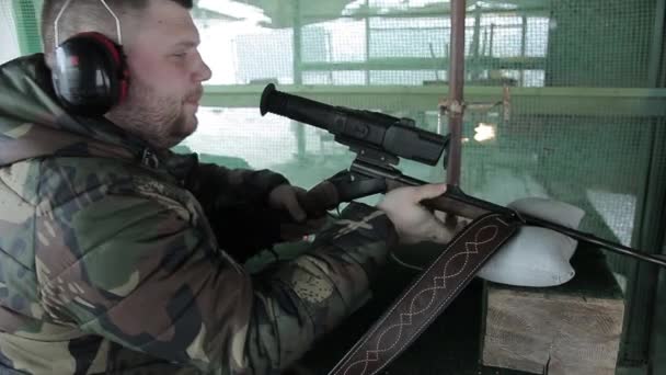 Ein männlicher Jäger schiebt eine Patrone in ein Gewehr, auf das ein Karabiner zielt, um sich auf einen Schuss aus einer Schusswaffe vorzubereiten. Schießtraining im Schießstand auf den Maschen. Mann in Tarnkleidung — Stockvideo