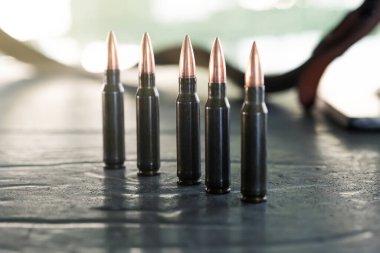 Karabina ya da tüfek fişekleri masanın üstünde duruyor. Çok sayıda vaka. Silahlı çatışma, savaş ya da çatışmayı gösteren pirinç cephane fişeklerinin arka planı