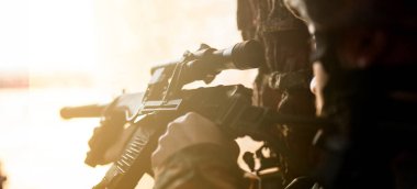 Savaştaki asker, elinde silahlarla düşmana nişan alır.