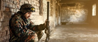 Harabelerin olduğu askeri operasyonda dinlenen düşünceli bir asker.