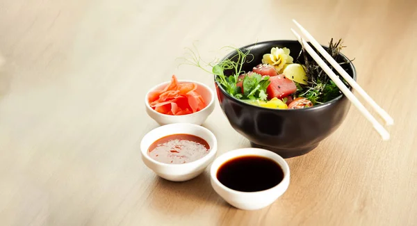 Sla met tonijn in een kom. Ingrediënten verse tonijn, kerstomaten, gemarineerd zeewier, rijst, takuan, Ponzu saus, Teriyaki saus, nori, sesamzaad, limoen, koriander. Aziatische zeevruchten salade concept. — Stockfoto