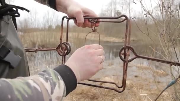 A male hunter sets a metal trap for a beaver. Beaver hunting in a trap on the river bank. Beaver hunting with a trap. — Stock Video