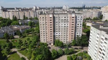 Endüstriyel bir dağcı iplere asılmış ve bir binanın duvarını silindirle boyuyor. Bir erkek işçi, çok katlı bir binanın dış cephesinin yalıtımı üzerinde çalışır. İnsansız hava aracından görüntüle.