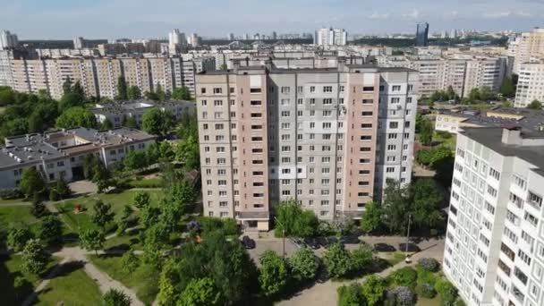 An industrial climber suspended on ropes and paints the wall of a building with a roller. A male worker performs work on the insulation of the facade of a multi-storey building. View from the drone. — Stock Video