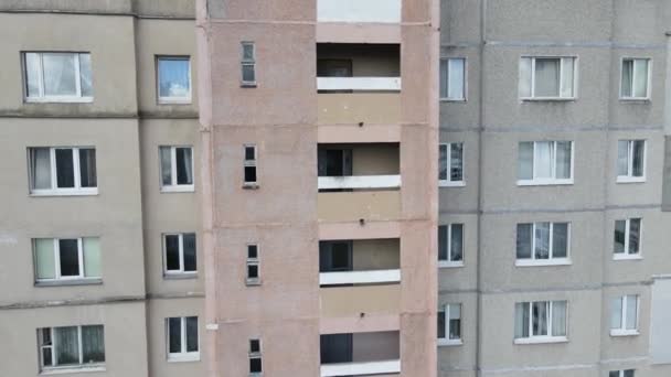 Un arrampicatore industriale sospeso su corde e dipinge la parete di un edificio con un rullo. Un lavoratore di sesso maschile svolge lavori sull'isolamento della facciata di un edificio a più piani. Vista dal drone. — Video Stock