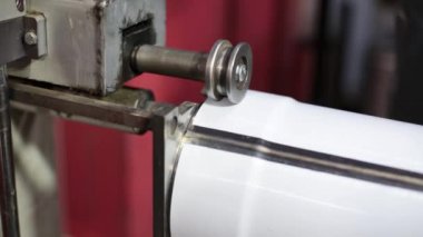 Havalandırma ve drenaj boruları üretiliyor. Bir adam üretim aracıyla çalışıyor, elektrikli bir makine. Metal levha bükmek için aletler ve ekipmanlar.