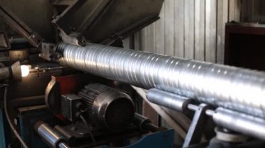 Makine paslanmaz çelik bir havalandırma borusu üretiyor. Havalandırma boruları üretmek için ekin. Fabrika metal havalandırma boruları üretiyor..