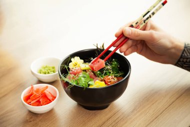 Çubuklu ton balıklı dürtme salatası yiyen bir adam. Ton balıklı salatayı bir kaseye koy. Restoranda salata yiyen genç bir adam. Asya deniz ürünleri salatası konsepti