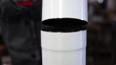 İşçi havalandırma sisteminin borularını bağlıyor. Adam metal boruları paslanmaz çelikle birleştirerek bir sistem kuruyor..