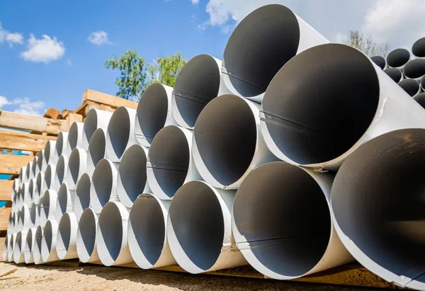 Aşağı boru deposu. Çelik borular, bir depoda çatı drenaj sistemi yapımında kullanılan parçalar. Bir yığın paslanmaz çelik boru.