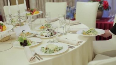 Garson restorandaki masaya koymak için bulaşıkları servis eder. Restorandaki erkek garson masaya sıcak et tabağı koyuyor.