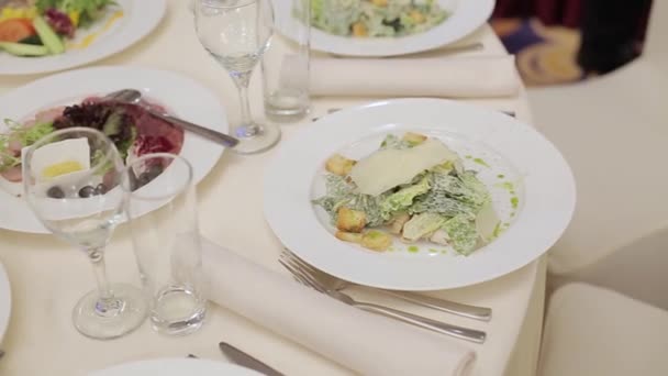 Servitören serverar rätter att ställa på bordet i restaurangen. Man servitör i en restaurang lägger tallrikar med varmt kött skålen på bordet — Stockvideo