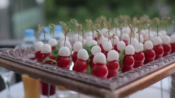 Tartine su un tavolo da buffet vassoio sulla terrazza. Patatine con mozzarella e pomodorini. — Video Stock