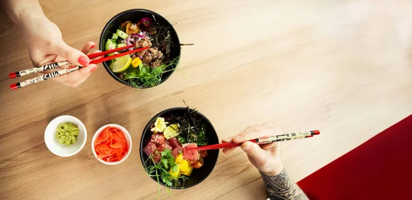 Любящие мужчина и женщина едят палочки для салата. Положите салат с тунцом в миску. Люди в ресторане едят салат с палочками. Азиатская концепция салата из морепродуктов. — стоковое фото