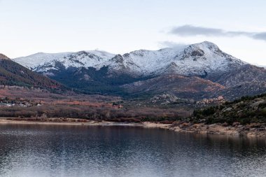 Navacerrada gölünde güneş doğuyor. Sierra de Guadarrama dağları karla kaplı.
