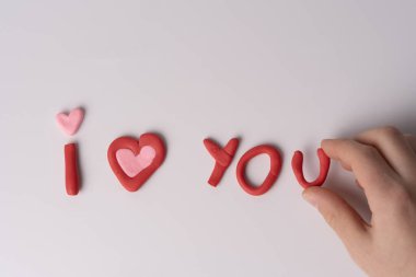 Beyaz bir yüzey üzerinde kırmızı çamurdan yapılmış, pembe bir kalp ve insani bir katılımla 