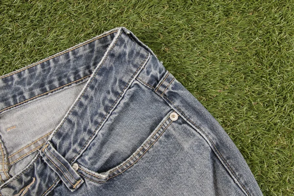 Calça jeans azul em um fundo de grama artificial — Fotografia de Stock