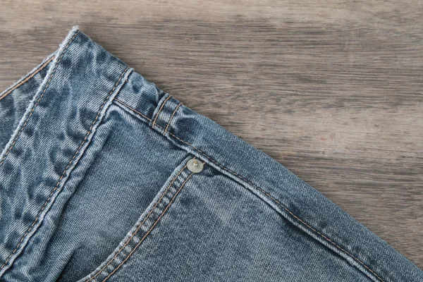 Modré džíny na hnědé dřevěné pozadí — Stock fotografie