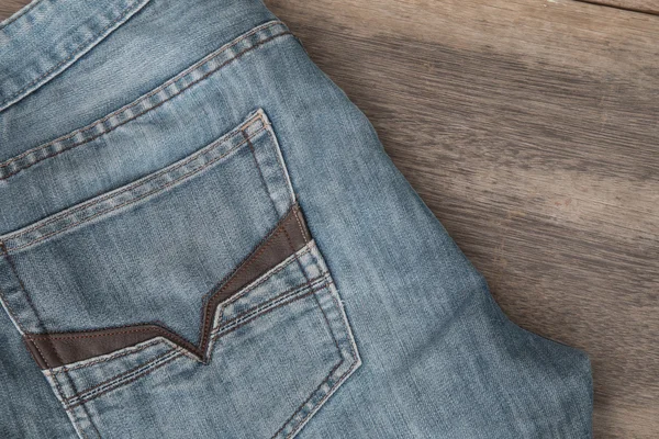 Calça jeans azul em um fundo de madeira marrom — Fotografia de Stock