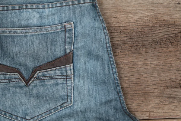 Calça jeans azul em um fundo de madeira marrom — Fotografia de Stock