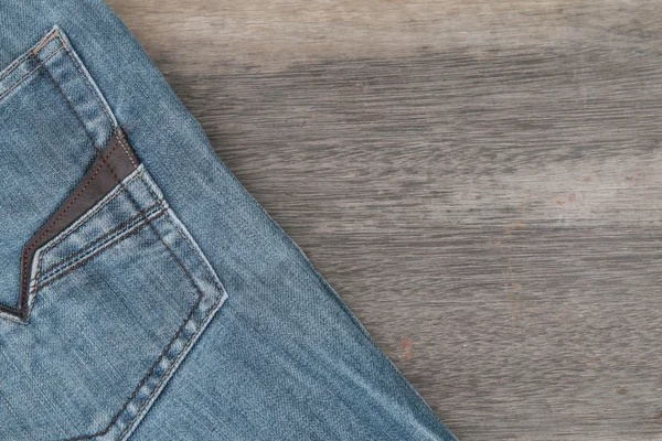 棕色木背景上的蓝色牛仔裤 — 图库照片