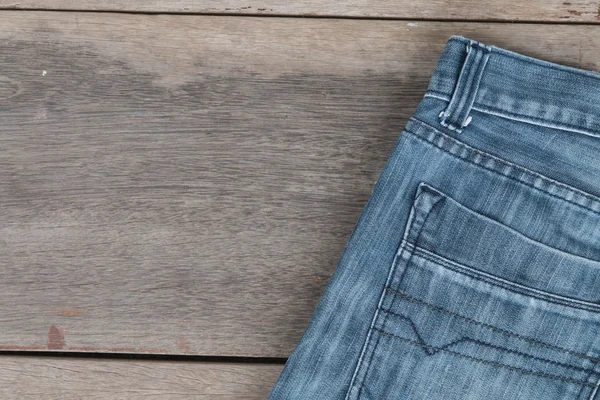 Calça jeans azul em um fundo de madeira marrom — Fotografia de Stock