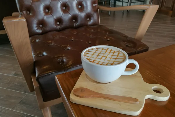 Καραμέλα Macchiato ζεστό καφέ στο φλιτζάνι λευκό με φόντο καφέ μπαρ — Φωτογραφία Αρχείου