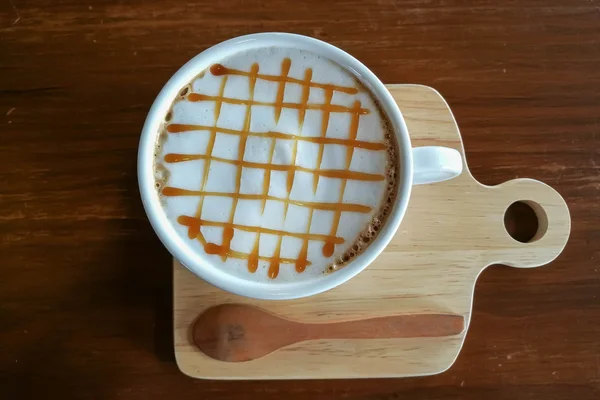 Καραμέλα Macchiato ζεστό καφέ στο φλιτζάνι λευκό στο τραπέζι Φωτογραφία Αρχείου