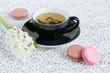 Fincan yeşil çay, renk acıbadem kurabiyesi ve beyaz çiçekler