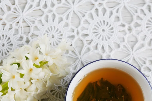 Чашка зеленого чая, цветной макарон и белые цветы — стоковое фото