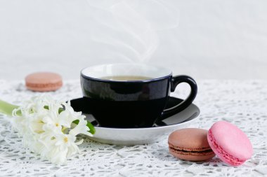 Fincan yeşil çay, renk acıbadem kurabiyesi ve beyaz çiçekler