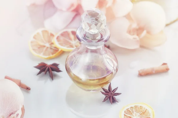 Spa Stilleven met parfumerende en aromatische oliën fles omgeven door bloemen en kaarsen, op lichte achtergrond — Stockfoto