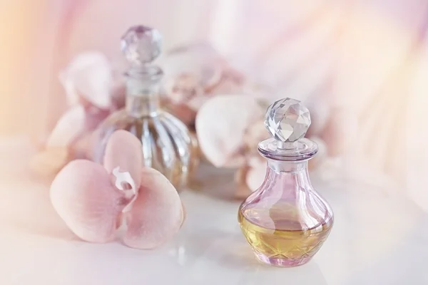 Frascos de perfume y aceites aromáticos rodeados de flores — Foto de Stock