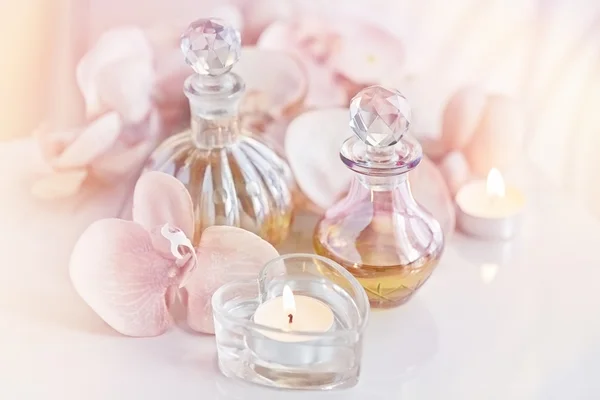 Zapachowych i aromatycznych olejów butelek otoczony kwiatami i cand — Zdjęcie stockowe